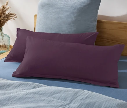 Deux oreillers violets sur un lit avec un drap bleu et un oreiller bleu en arrière-plan.