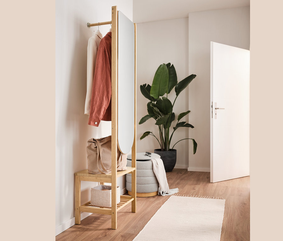 Pouf avec espace de rangement, sac, vêtements et portant à vêtements avec miroir dans un intérieur.