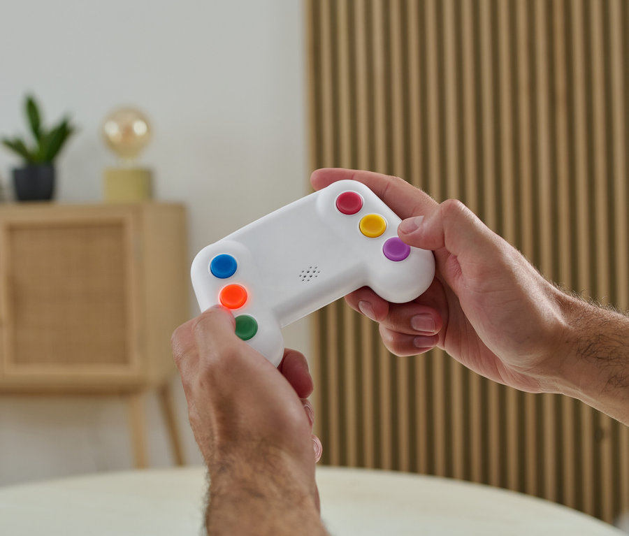 Un homme tient dans ses mains un entraîneur de mémoire électronique avec des boutons colorés.