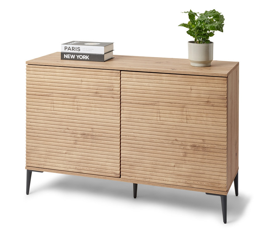 Un buffet « REET » avec aspect lamellé se trouve dans la pièce. Des livres et une plante en pot sont posés sur le buffet.