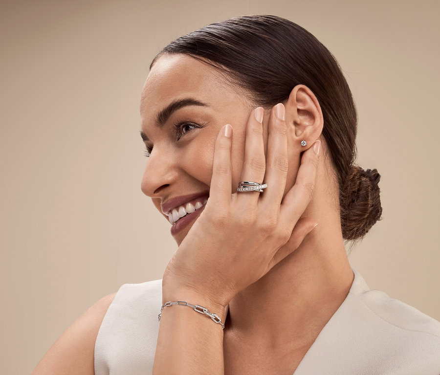 Une femme avec une bague et un bracelet en argent sourit et regarde vers la gauche.