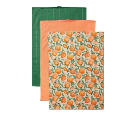 Un ensemble de 3 linges de cuisine : un vert à rayures, un orange et un blanc avec un imprimé d’oranges.