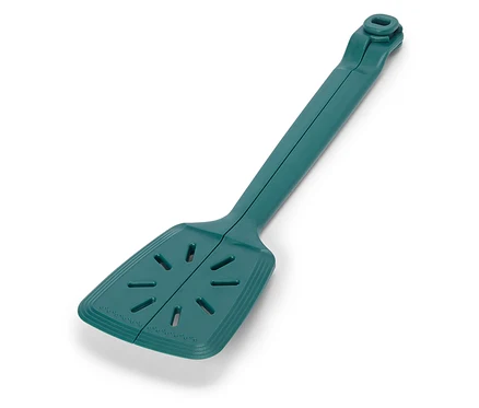 Une spatule unique, longue et verte est posée sur un fond blanc.