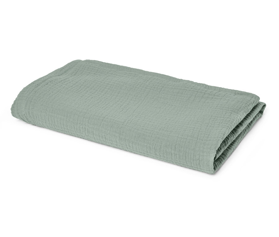 Couverture en mousseline vert clair pliée sur fond blanc.