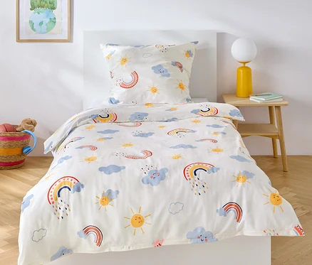 Linge de lit enfant Renforcé, taille standard, avec motif arc-en-ciel, nuages et soleil sur un lit.