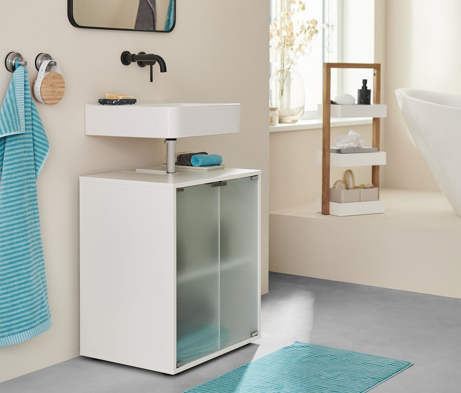 Salle de bain avec meuble sous vasque, tapis de bain turquoise et serviettes.