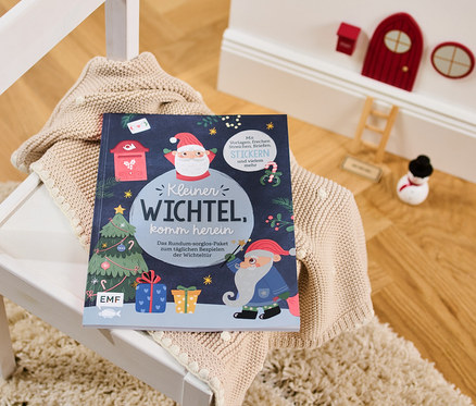 Le livre : « Kleiner Wichtel, komm herein » (Entre, petit lutin, en allemand) est posé sur un pull sur une chaise blanche.