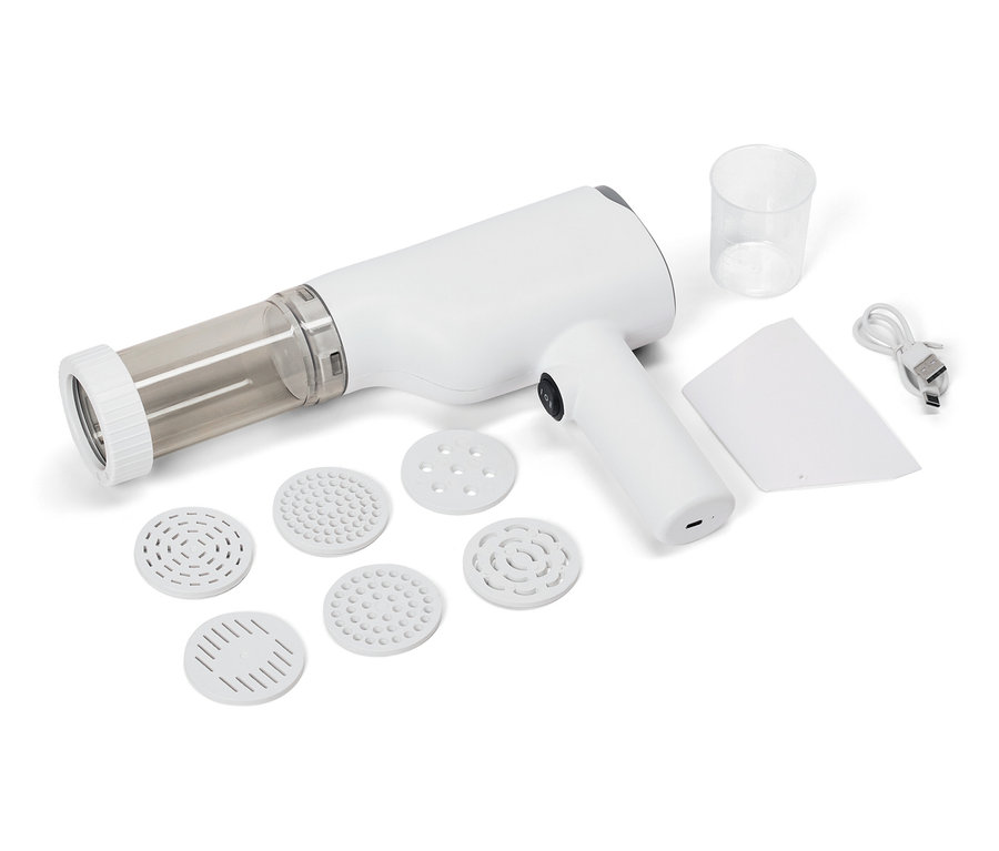 Machine à pâtes électrique avec différents accessoires, verre doseur, spatule et câble de charge sur fond blanc.