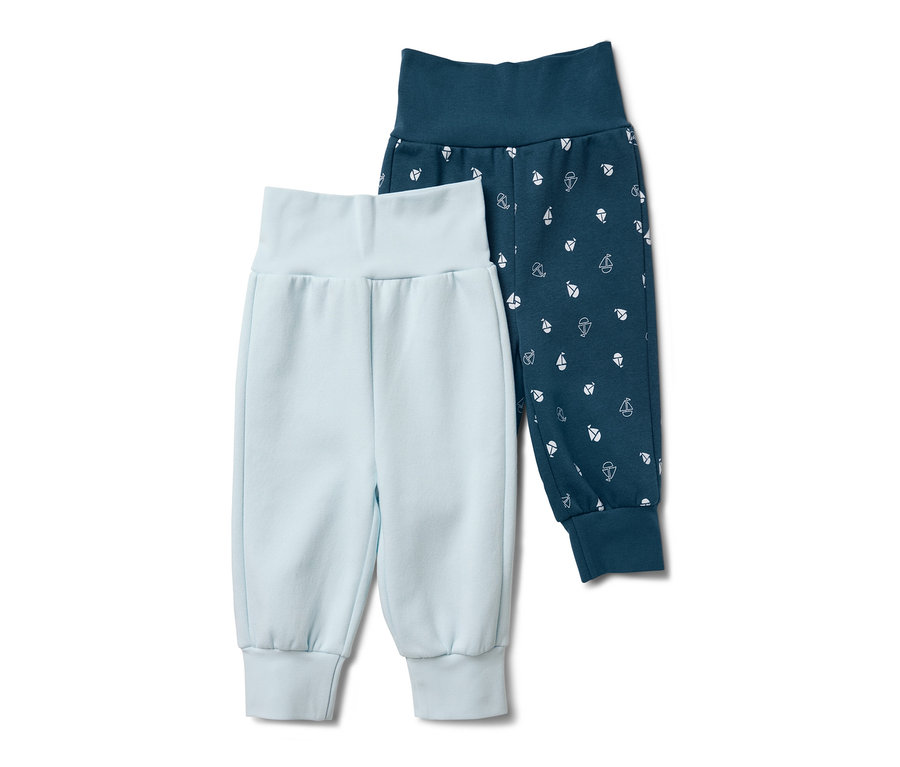 Deux pantalons de survêtement pour bébé : un bleu clair et un bleu foncé avec des petits voiliers blancs.
