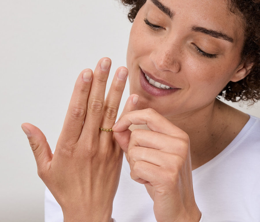 Femme regardant une bague en or à son doigt.