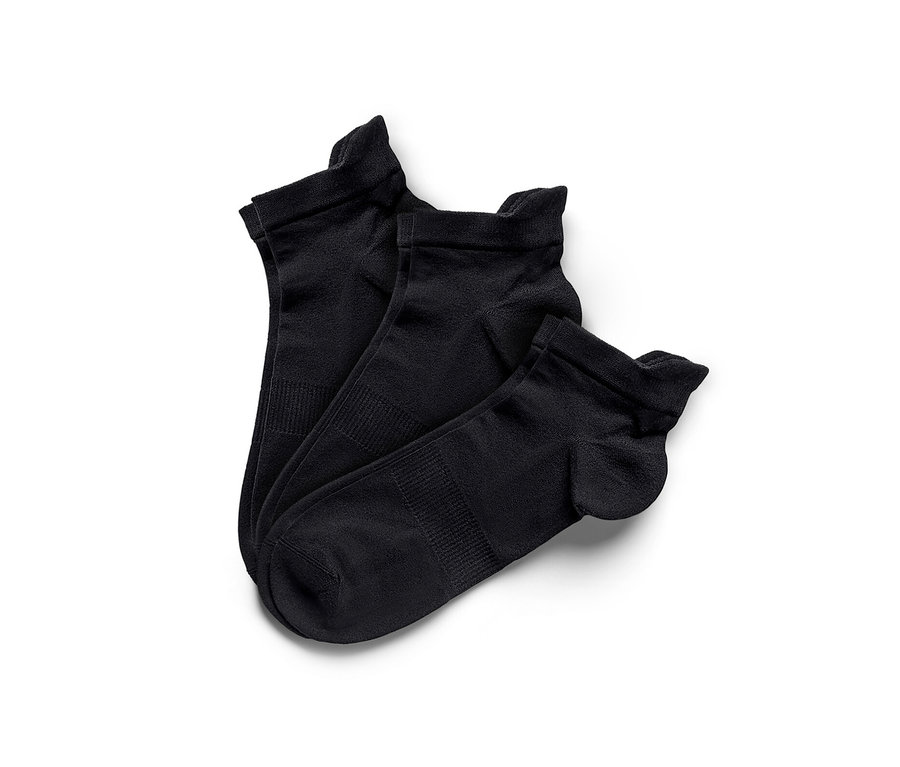 Trois paires de chaussettes de sport techniques noires sur fond blanc.