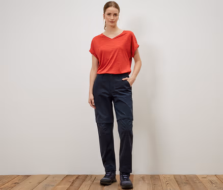 Femme debout portant un t-shirt rouge et un pantalon fonctionnel 2 en 1 bleu.
