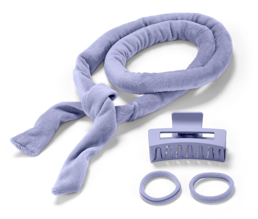 Un bigoudi en tissu éponge lilas, une pince à cheveux et deux élastiques à cheveux sur fond blanc.