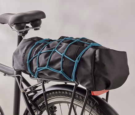 Un sac de vélo noir est fixé à un porte-bagages de vélo noir à l'aide d'un filet à bagages bleu.