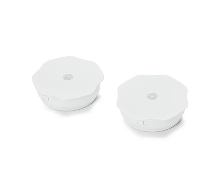 Deux lumières rondes blanches de palet reposent sur une surface blanche.