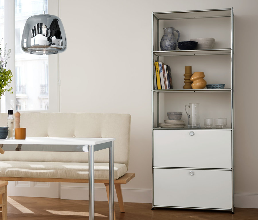 Intérieur de salle à manger avec lustre en chrome, table en métal, étagère avec tiroirs et chaises de salle à manger.