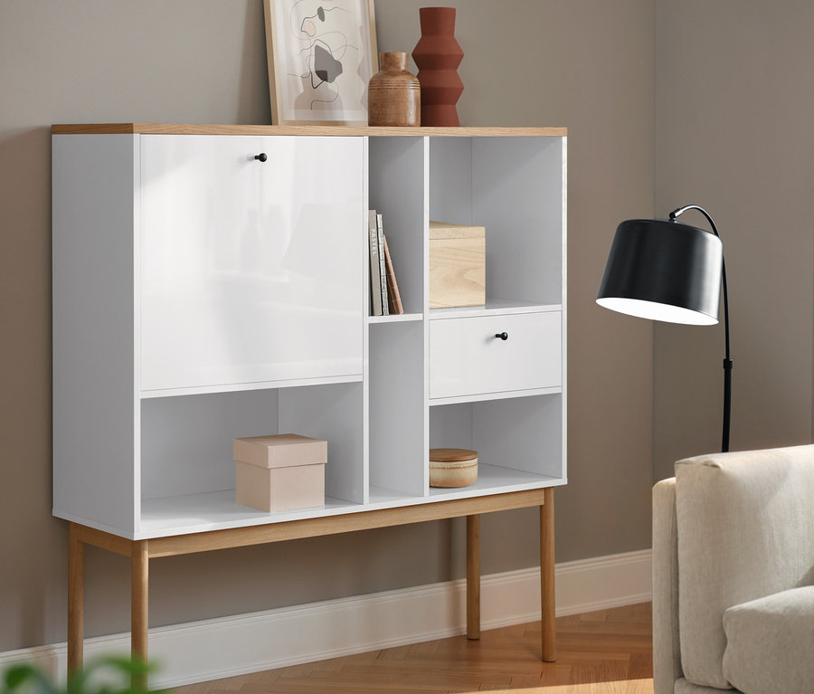 Un secrétaire blanc et une lampe de table noire en métal dans un salon.