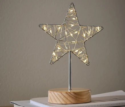 Une figurine décorative à LED « Étoile » posée sur des livres sur une armoire.