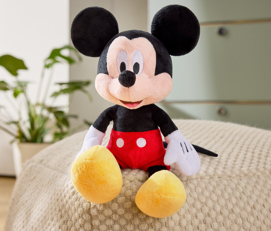 Une peluche de Mickey Mouse est assise sur un pouf.