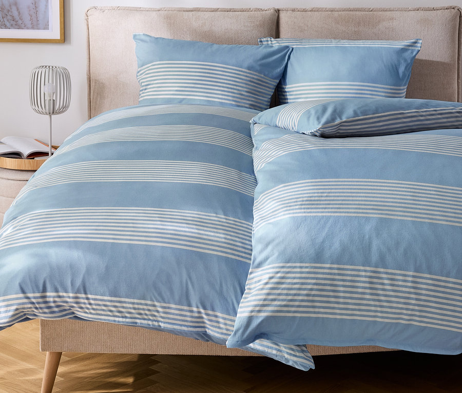 Lit avec des draps et des oreillers rayés bleu et blanc.