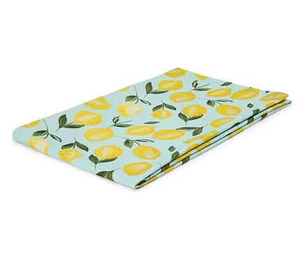 Un tissu bleu clair plié avec un motif de citrons jaunes et de feuilles vertes repose sur un fond blanc.