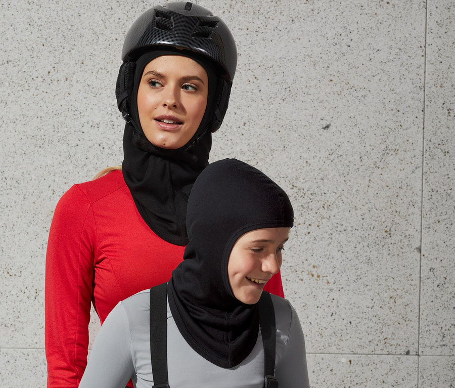 Une femme portant un casque et une cagoule Performance se tient derrière un garçon portant une cagoule.