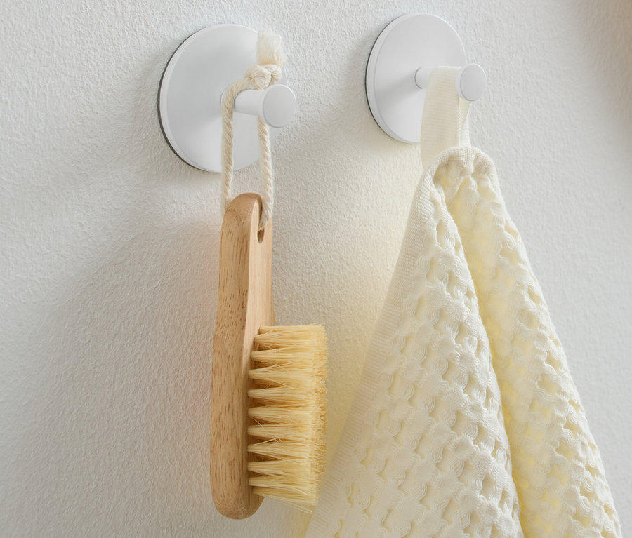 Deux crochets sur le mur, une brosse suspendue à l'une et une serviette à l'autre.
