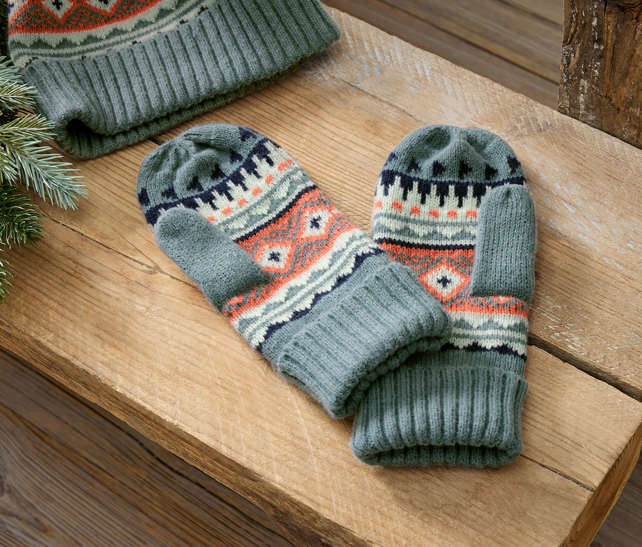 Des moufles et un bonnet tricotés gris avec un motif norvégien reposent sur une surface en bois.