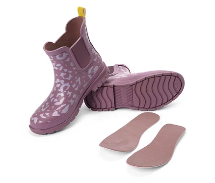 Deux bottes en caoutchouc violettes à motif blanc et languette jaune, à côté de deux semelles intérieures.