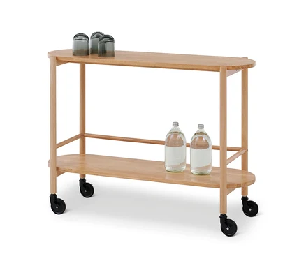 Un chariot de service ovale en bois clair avec deux étagères. Trois verres foncés retournés sont sur l'étagère supérieure, et deux bouteilles d'eau sur l'étagère inférieure. Le chariot a des roulettes noires.
