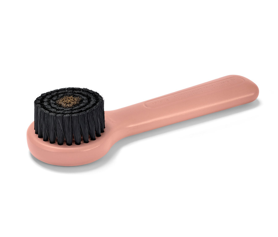 Gros plan sur une brosse de massage du visage en cuivre rose.