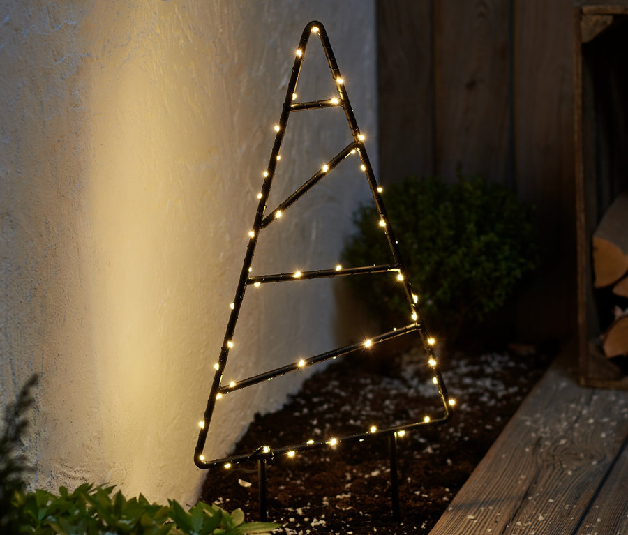 Un petit sapin d'extérieur à LED en métal est posé sur le sol à côté d'une allée en bois.