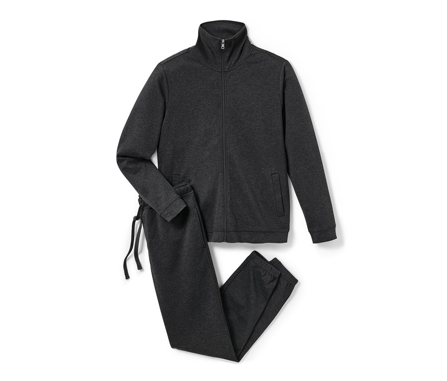 Un survêtement d’intérieur gris avec fermeture éclair et cordon de serrage repose sur un fond blanc.