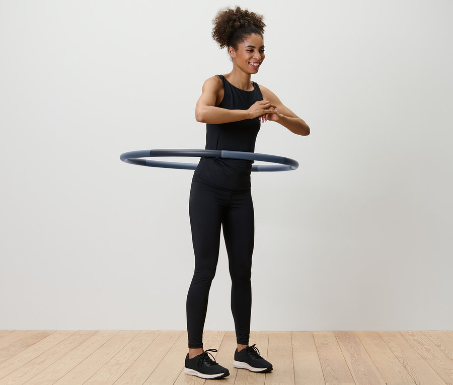 Femme faisant tourner un cerceau de fitness autour de sa taille.