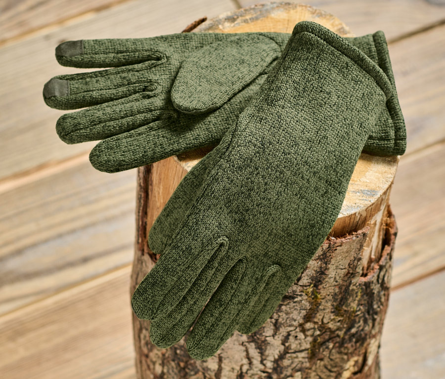 Des gants en polaire tricotée kaki sont posés sur une bûche de bois.