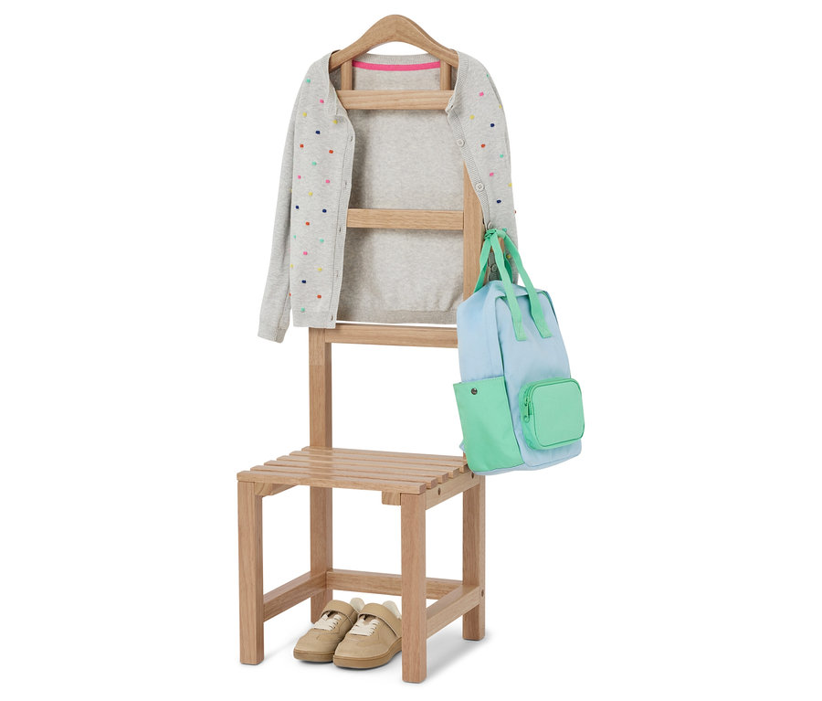 Un cardigan gris à pois colorés est accroché à une chaise avec un sac bleu clair et vert. Des chaussures beiges sont placées sous la chaise.