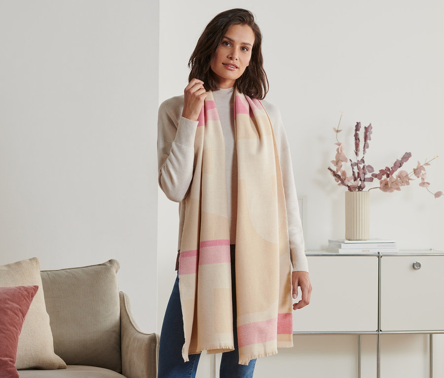 Femme posant avec une écharpe à franges beige et rose.
