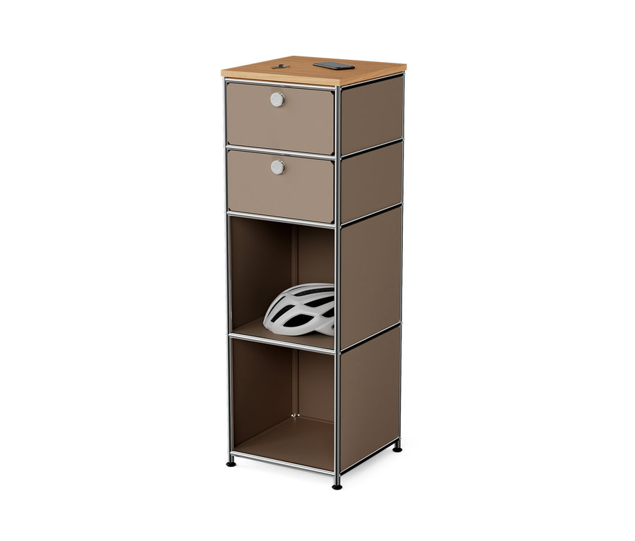 Commode étroite en métal « CN3 » avec plateau en bois et 2 tiroirs, taupe. Un casque blanc repose dans le compartiment ouvert.