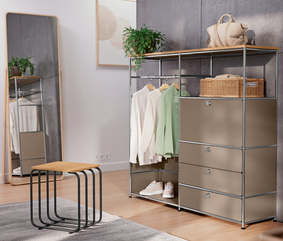 Dans une pièce, commode en métal « CN3 » taupe avec plateau en bois, tringle, abattant et 3 tiroirs, tabouret et miroir.