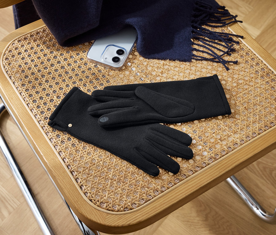 Sur une chaise sont posés des gants noirs, un téléphone et une écharpe.