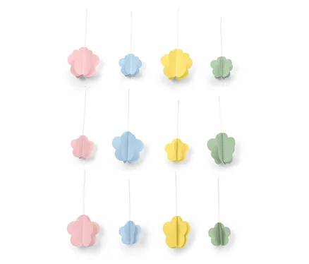 Des fleurs décoratives en papier rose, bleu, jaune et vert sont suspendues à des fils devant un fond blanc.