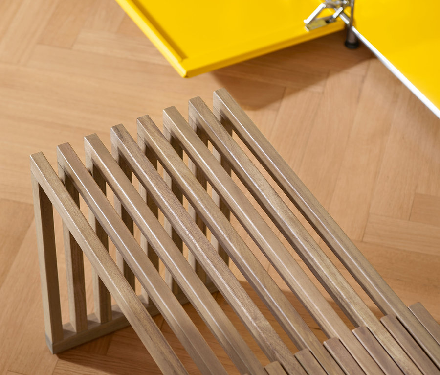 Gros plan sur un banc convertible et une armoire jaune sur un parquet.