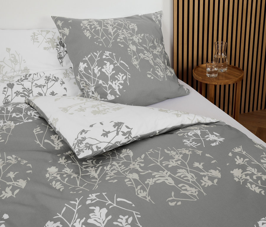Parure de lit grise en renforcé avec motif floral sur un lit.
