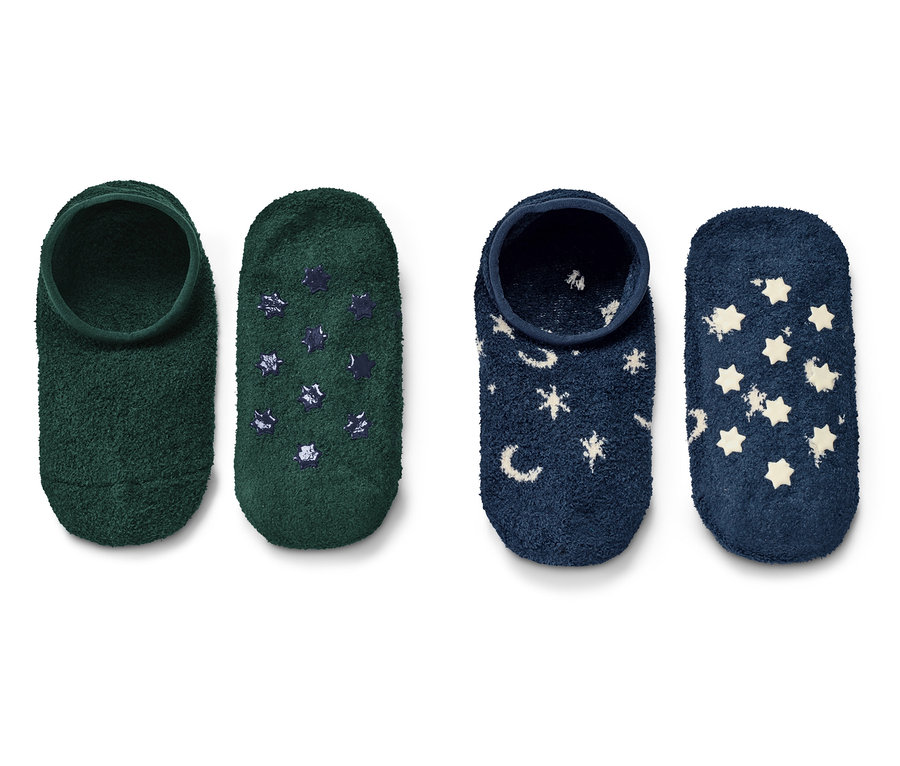 Deux paires de chaussons à enfiler. Une paire est verte avec des étoiles bleu foncé, l'autre bleu foncé avec des étoiles blanches et des lunes.