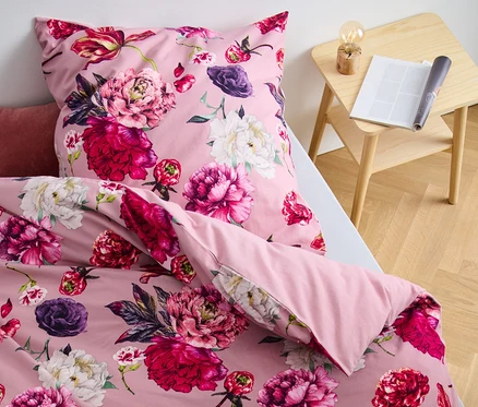 Gros plan d'une parure de lit en molleton rose à motifs floraux sur un lit.