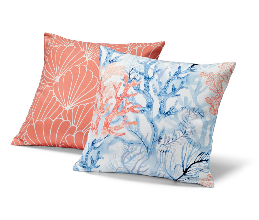 Deux housses de coussin décoratif : une corail avec un motif géométrique blanc, l’autre avec des coraux bleus et corail.