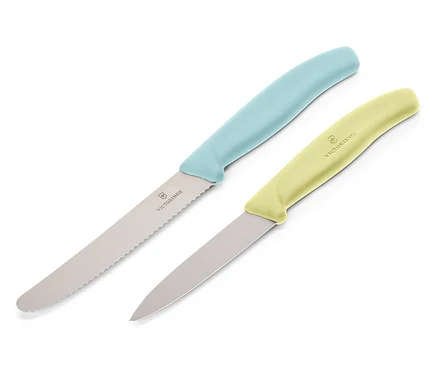 Deux couteaux Victorinox sont disposés en diagonale sur un fond blanc. Le couteau supérieur a un manche bleu clair et une lame dentelée, le couteau inférieur a un manche jaune clair et une lame lisse.
