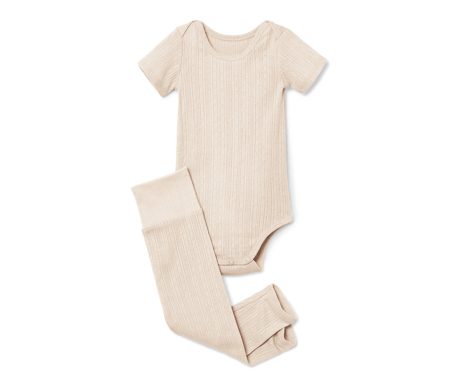 Un body et leggings pour bébé beiges sont posés sur un fond blanc.