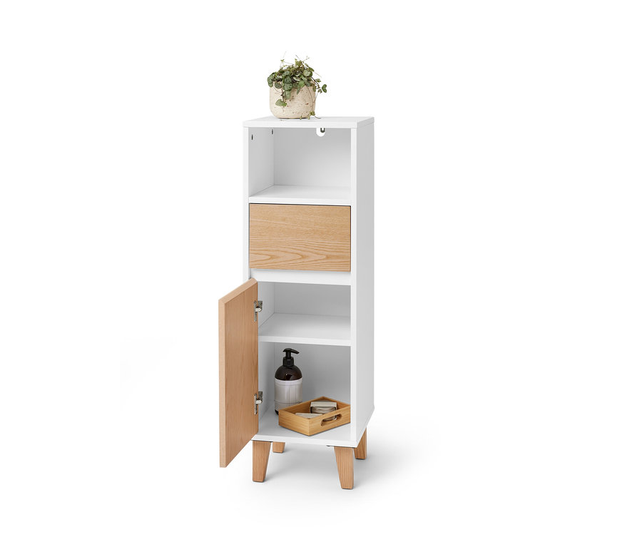 Armoire de salle de bain étroite avec tiroir et porte, avec une plante dessus.