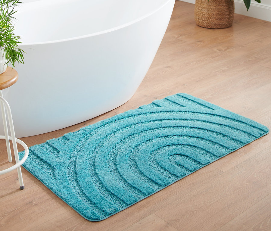 Un tapis de bain turquoise wellness, env. 70 x 120 cm, posé sur un plancher en bois à côté d'une baignoire blanche.